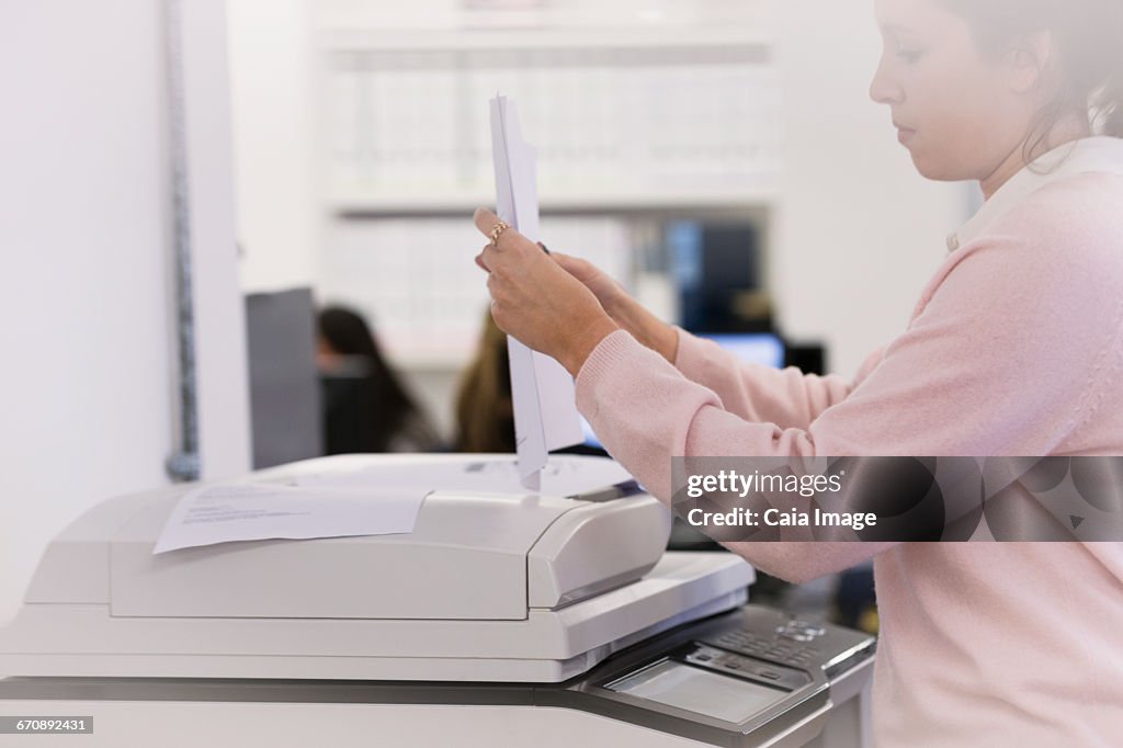 Businesswoman making copies at photocopier in office