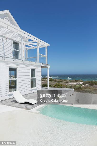 white beach house and swimming pool with ocean view under sunny blue sky - beach house exterior stock pictures, royalty-free photos & images
