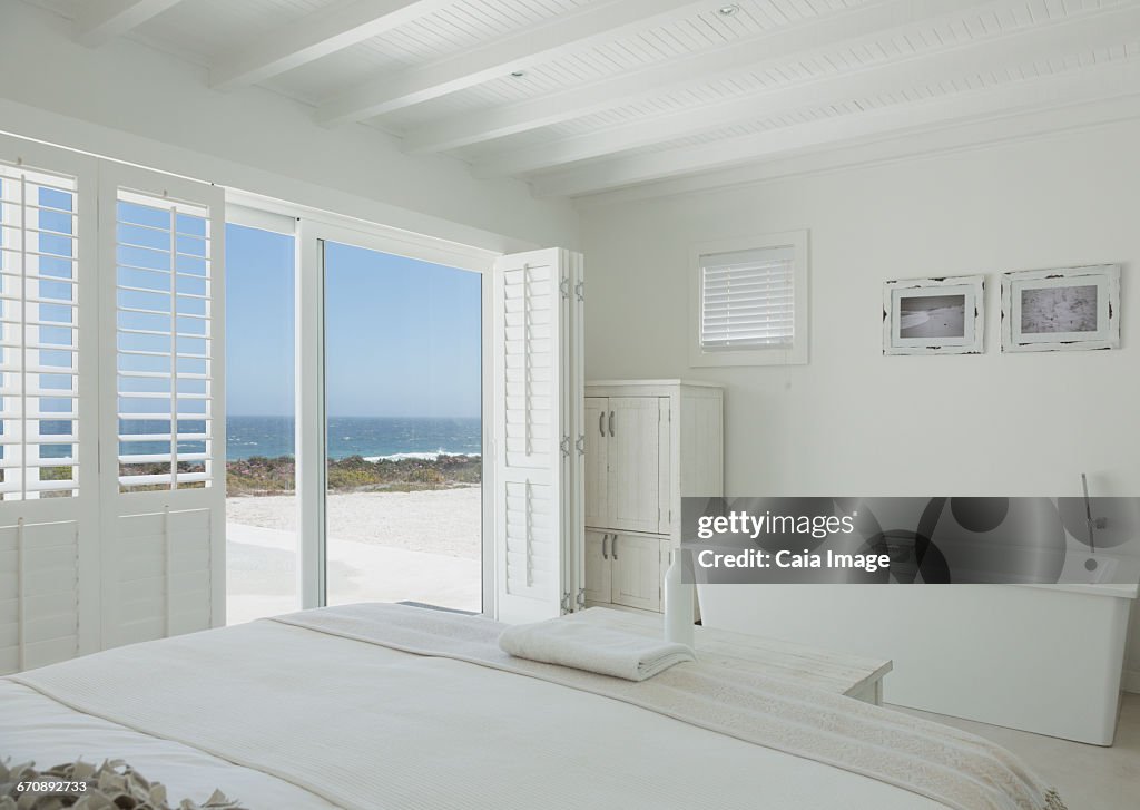 White hotel room with en suite soaking tub and ocean view