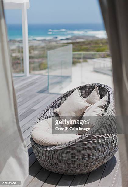 wicker seat with cushions on sunny beach house deck with ocean view - beach house balcony stock pictures, royalty-free photos & images