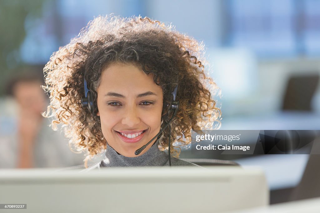 Businesswoman with headset working at computer in office