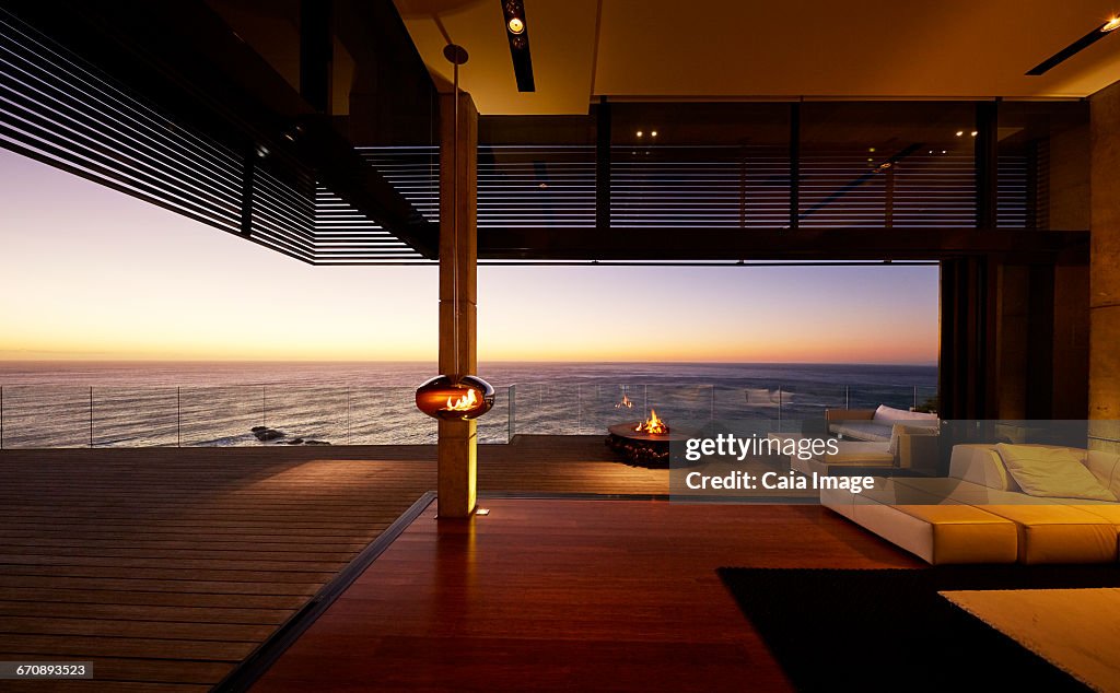 Fire pit and hanging fireplace on modern luxury patio with sunset ocean view