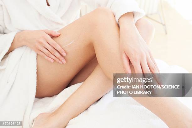 young woman applying cream to leg - hamstring stock pictures, royalty-free photos & images