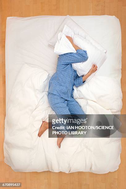 woman lying in bed with pillow over head - covers head with pillow stock-fotos und bilder