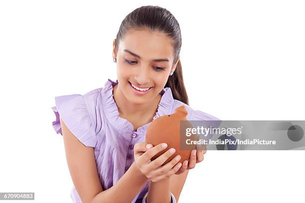 smiling teenage girls holding a money bank in her hands - gullak stock-fotos und bilder