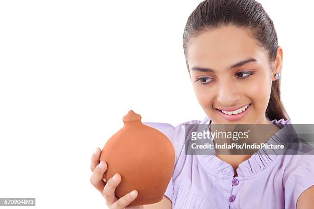 smiling teenage girls holding a money bank in her hands - gullak stock-fotos und bilder