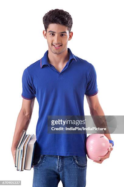 a young student holding books in one hand and money bank in the other - gullak stock-fotos und bilder