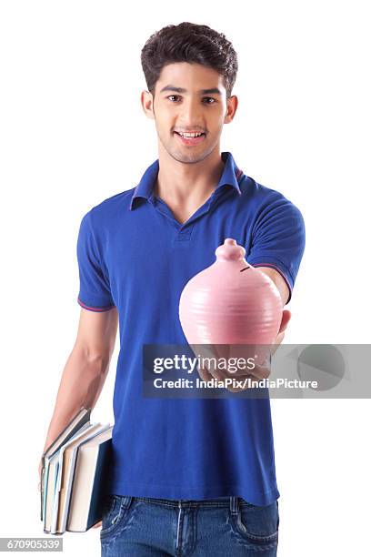 a young student holding books in one hand and money bank in the other - gullak bildbanksfoton och bilder