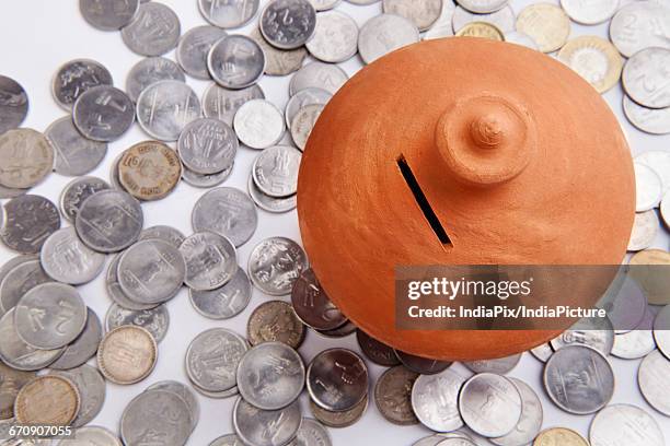 pink piggy bank standing on coins heap - gullak stock-fotos und bilder