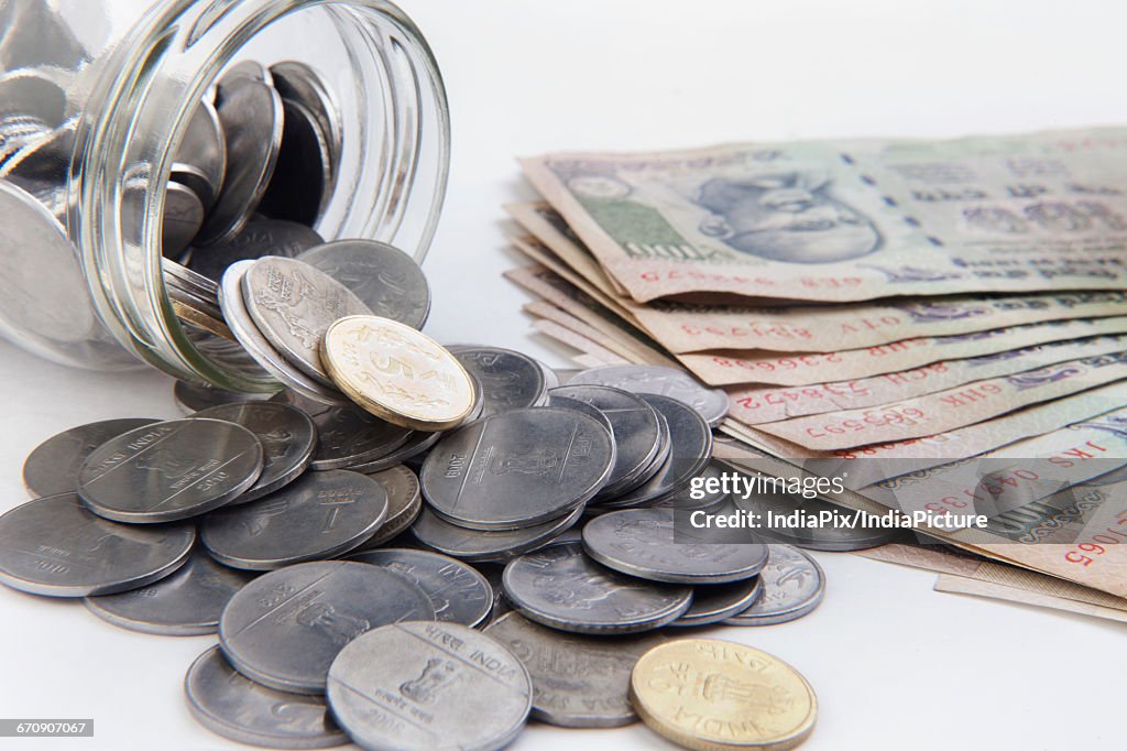 Coins in a mason jar over white background