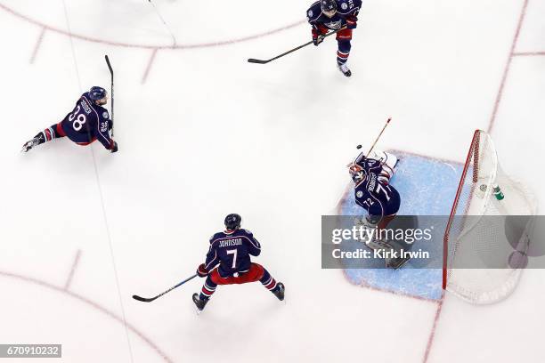 Sergei Bobrovsky of the Columbus Blue Jackets stops a shot as Jack Johnson, Boone Jenner, and David Savard, all of the Columbus Blue Jackets, fall...