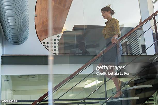 businesswoman descending office staircase - down fotografías e imágenes de stock