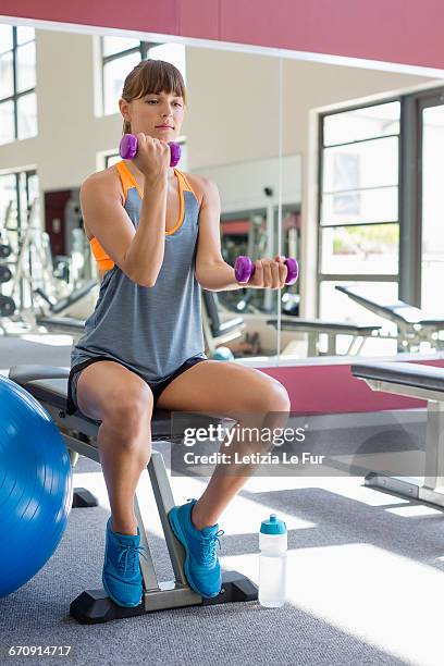 young woman exercising with dumbbells in a fitness club - gym excercise ball stock pictures, royalty-free photos & images