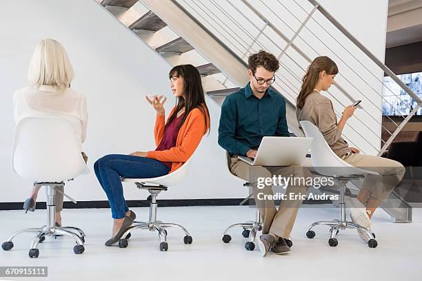 business executives sitting on chairs busy in different activities - office chair back fotografías e imágenes de stock