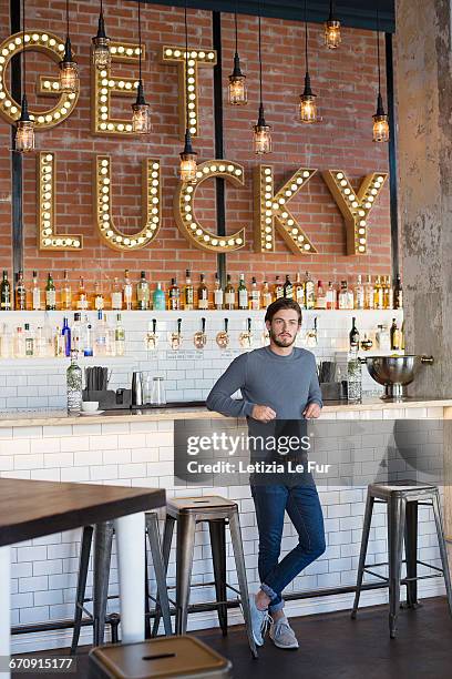 young man standing at bar counter - stool imagens e fotografias de stock