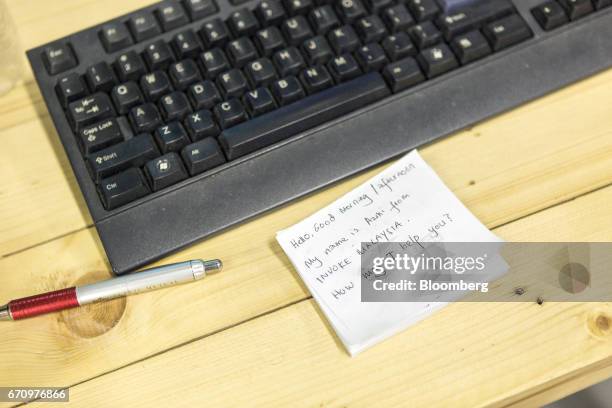 Note pad with a script written on it sits next to a computer keyboard in the call center at Invoke's office in Kuala Lumpur, Malaysia, on Tuesday,...