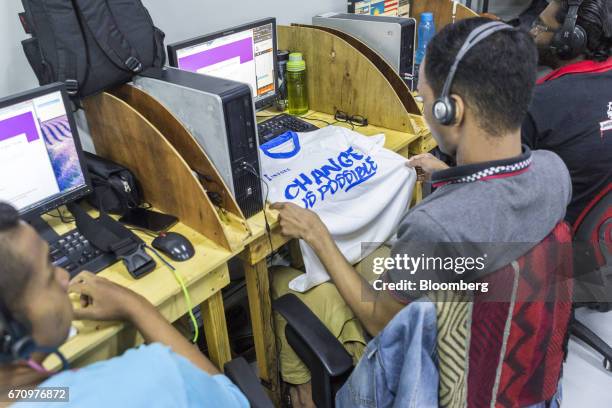 An employee looks at a t-shirt that reads 'Change Is Possible' in the call center at Invoke's office in Kuala Lumpur, Malaysia, on Tuesday, April 18,...