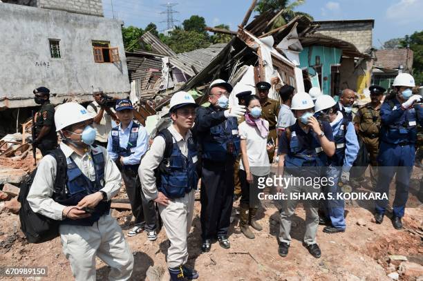 Japanese officials with a disaster relief team survey the site of a garbage dump collapse that killed 32 people on the northeastern edge of Sri...