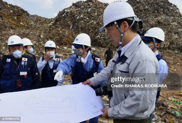 Japanese officials with a disaster relief team survey the site of a garbage dump collapse that killed 32 people on the northeastern edge of Sri...