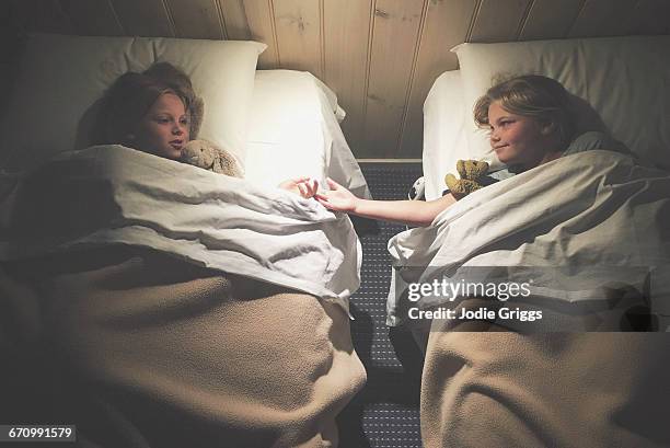 sisters lying in separate beds talking together - jodie griggs stock pictures, royalty-free photos & images