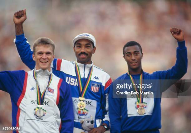 Greg Foster of the United States celebrates his gold medal with silver medallist Jonathan Ridgeon and bronze medallist Colin Jackson of Great Britain...