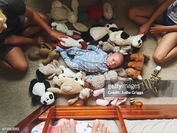 older siblings playing with infant on the floor - jodie griggs stock pictures, royalty-free photos & images