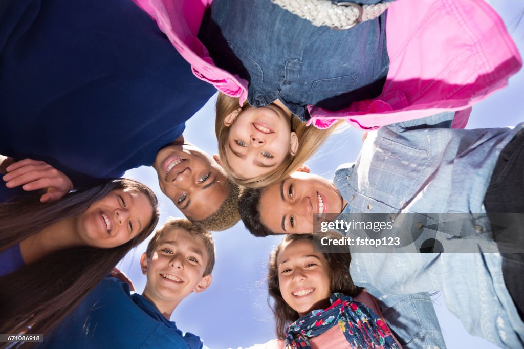 Multi-ethnic group of pre-teenagers hanging out in park with friends.