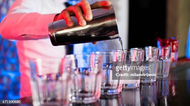 barkeeper mixen getränke in cocktail-bar - blue martini glasses stock-fotos und bilder