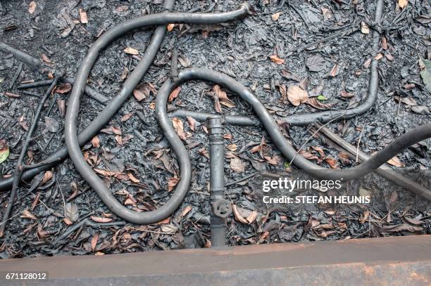 Disconnected pipe lies on the ground at the outlet of an illegal oil refinery storage tank on April 19, 2017 in the Niger Delta region near the city...