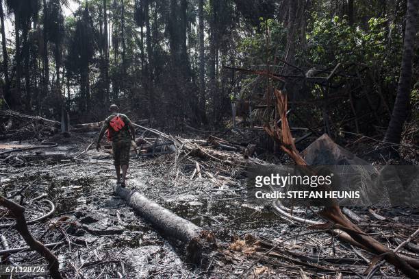 Members of the NNS Pathfinder of the Nigerian Navy forces walks through the oil covered environment of a destroyed illegal oil refinery on April 19,...