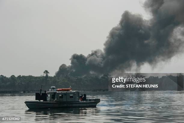 Cloud of smoke rises from an illegal oil refinery on April 19, 2017 in the Niger Delta region near the city of Port Harcourt. NNS Pathfinder of the...