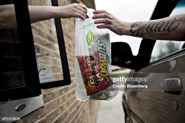 An employee passes an order to a customer at the drive-thru of a Subway Restaurants location in Princeton, Illinois, U.S., on Thursday, April 20,...