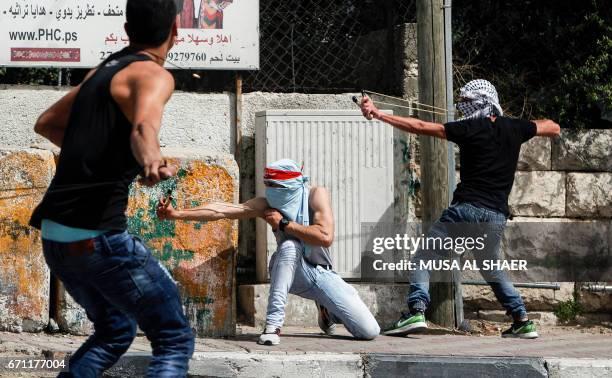 Palestinian protesters use slingshots to hurl stones towards Israeli security forces during clashes following a demonstration in the West Bank town...