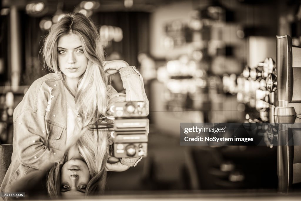 Mooie blonde meisje met retro camera indoor portret, café pub interieur