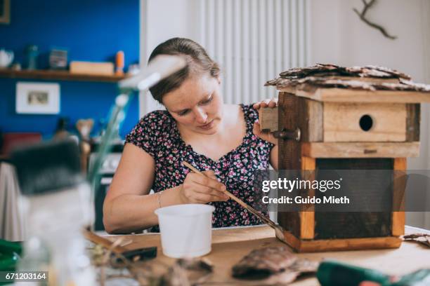 woman painting a bird house. - basteln stock-fotos und bilder