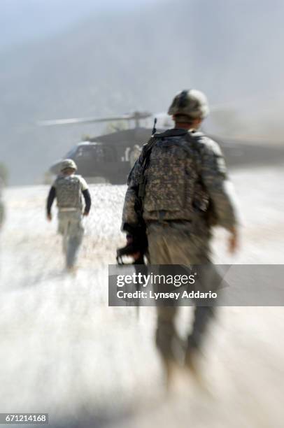 Soldiers from the 173rd division walk off of a blackhawk and to the KOP base in the mountains of Kunar, Afghanistan after attending a memorial...