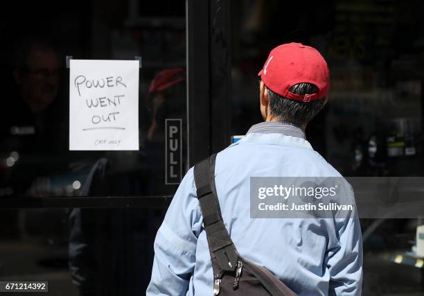 Pedestrian looks at a sign posted on the door of a hardware store during a citywide power outage on April 21, 2017 in San Francisco, California....