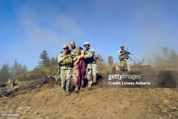 Specialist Carl Vandeberge, center, and Sergeant Kevin Rice, behind, are assisted as they walk to a medevac helicopter minutes after they were both...
