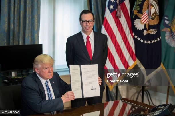 President Donald Trump , with Secretary of Treasury Steven Mnuchin , displays a signed financial services Executive Order during a ceremony in the US...