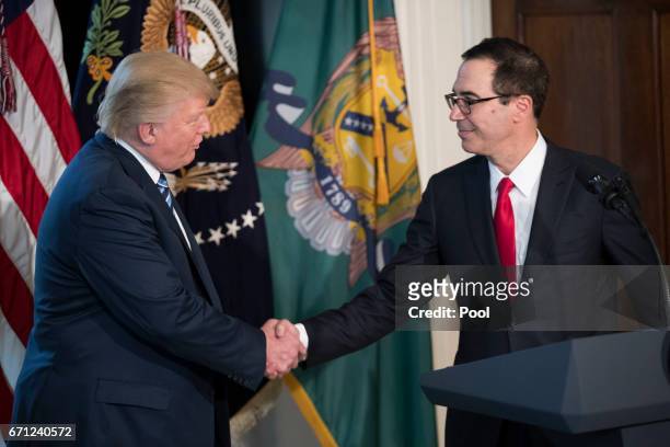President Donald Trump shakes hands with Secretary of Treasury Steven Mnuchin during a ceremony in the US Treasury Department building on April 21,...