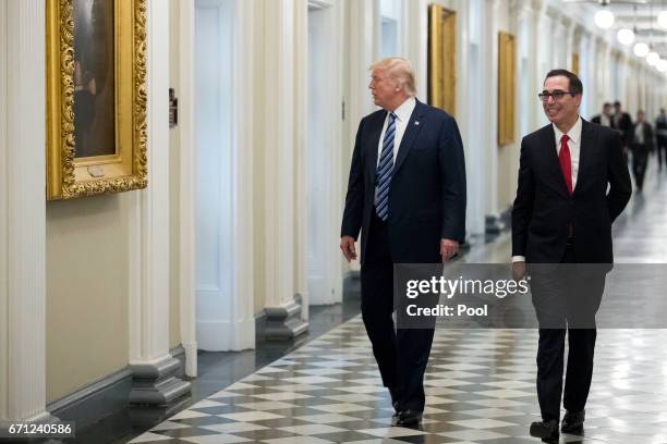 President Donald Trump and Secretary of Treasury Steven Mnuchin walk to a meeting in the US Treasury Department building on April 21, 2017 in...