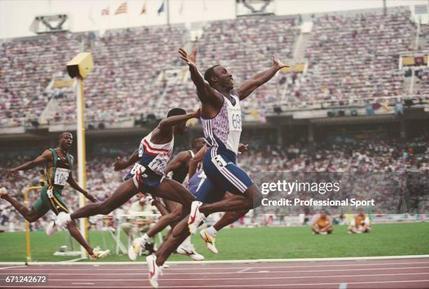 British track and field athlete Linford Christie of the Great Britain team raises his arms in the air as he crosses the finish line in first place to...
