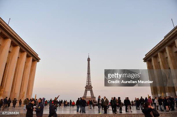 Tourists are seen on the Trocadero in front of the Eiffel Tower the day after a gunman opened fire on police officers on the Champs Elysees on April...