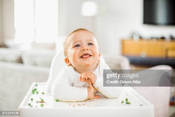 niño comiendo guisantes verdes - bebe 1 a 2 años fotografías e imágenes de stock