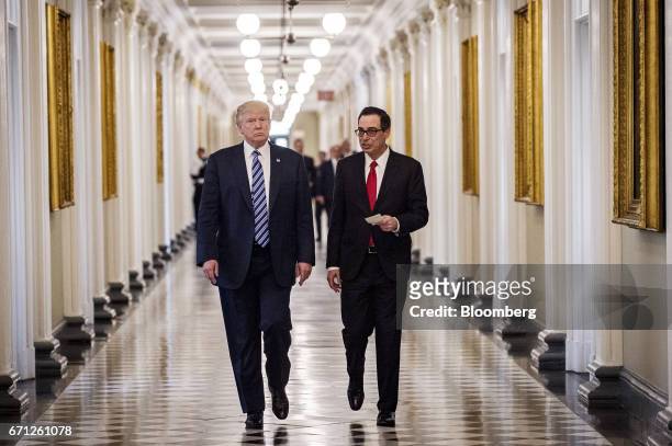 President Donald Trump, left, and Steven Mnuchin, U.S. Treasury secretary, walk down the hall of the Treasury Department building before signing an...