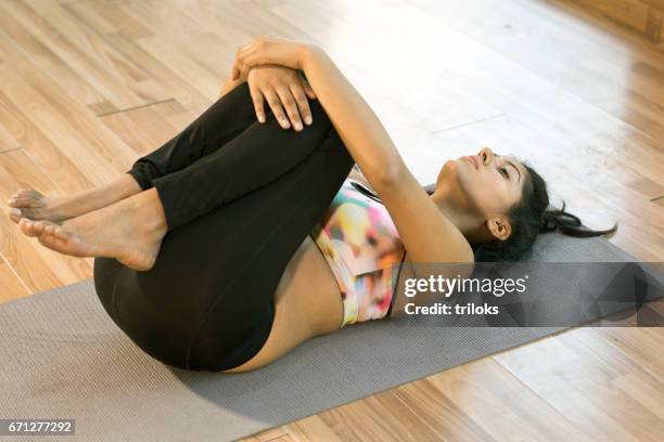 jeune femme dans une pose d’yoga apanasana - position du foetus photos et images de collection