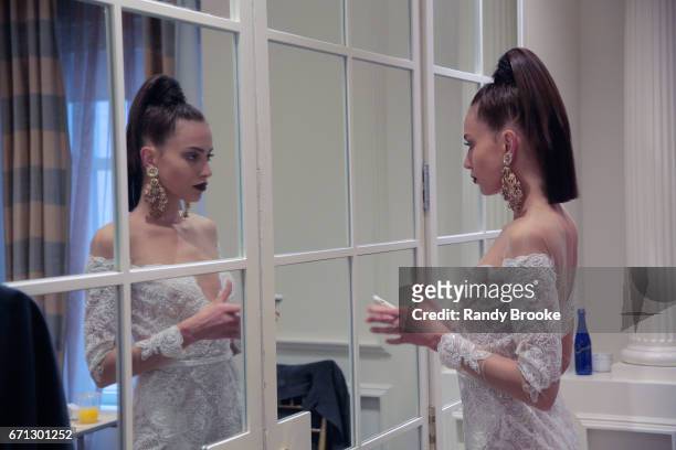 Model checks out her cell phone backstage at the Berta Runway show during New York Fashion Week: Bridal April 2017 at The Plaza Hotel on April 21,...
