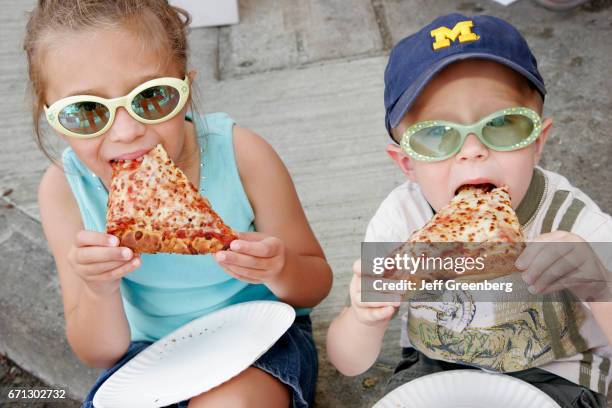 Boy and girl eating sliced pizza at Art Fairs.