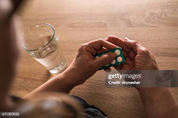 onherkenbaar senior vrouw nemen van een pil met een glas water. - pillen nemen stockfoto's en -beelden