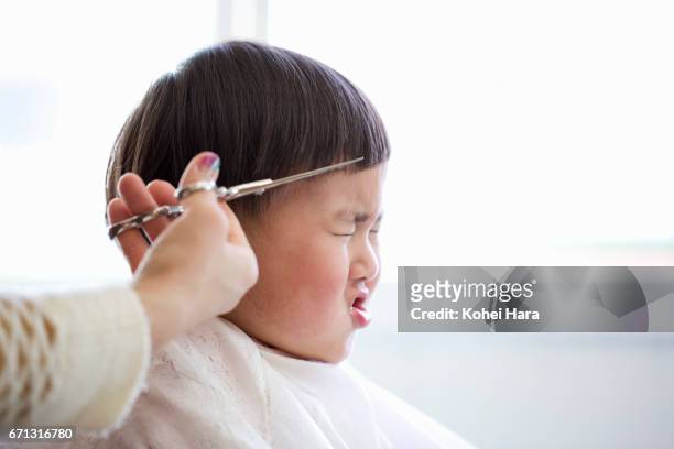 a boy having his hair cut by female beautician in a beauty salon - offbeat imagens e fotografias de stock